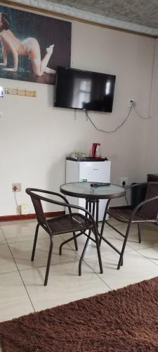 a table and chairs in a room with a television at Whitehouse Lodge Benoni in Benoni