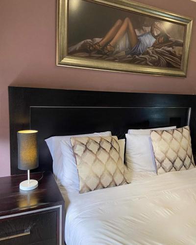 a bedroom with a bed with a painting on the wall at Whitehouse Lodge Benoni in Benoni