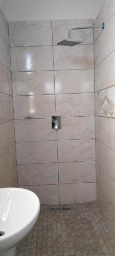 a bathroom with a shower with a white sink at Whitehouse Lodge Benoni in Benoni
