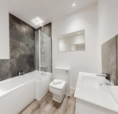 een badkamer met een toilet, een bad en een wastafel bij Spacious two bedroom apartment with Valley views in Abertillery