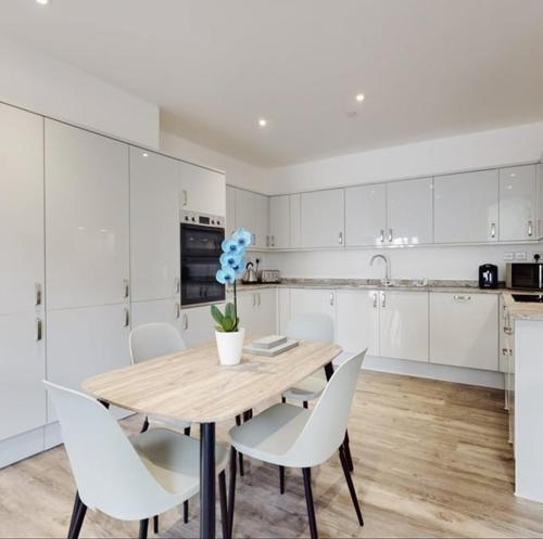 a kitchen with a wooden table and white cabinets at Spacious two bedroom apartment with Valley views in Abertillery