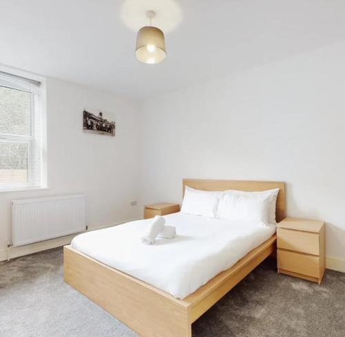 een slaapkamer met een groot bed met witte lakens bij Spacious two bedroom apartment with Valley views in Abertillery