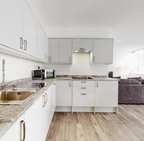 a white kitchen with white cabinets and a sink at Spacious two bedroom apartment with Valley views in Abertillery