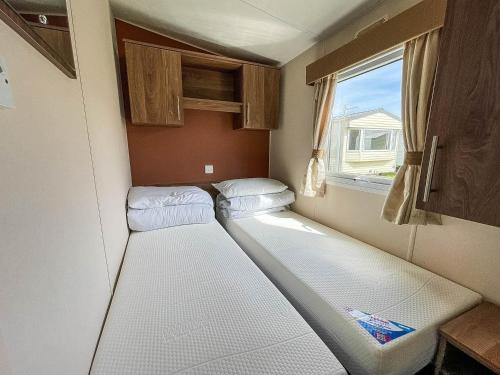 Duas camas num pequeno quarto com uma janela em Lovely 8 Berth Caravan With Decking At Sunnydale Park, Lincolnshire Ref 35091br em Louth