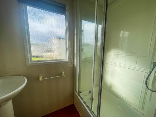 a bathroom with a shower and a sink and a window at 6 Berth Caravan With Decking Nearby Heacham Beach In Norfolk Ref 21047a in Heacham