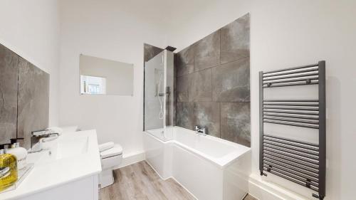 a white bathroom with a sink and a toilet at Spacious three bedroom apartment with Valley views in Abertillery