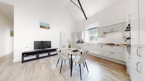 a kitchen with white cabinets and a table and chairs at Spacious three bedroom apartment with Valley views in Abertillery