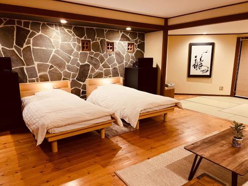 a bedroom with two beds and a stone wall at Yufuin Tsukawara Kogen Sanctuary - Vacation STAY 91378v in Yufuin