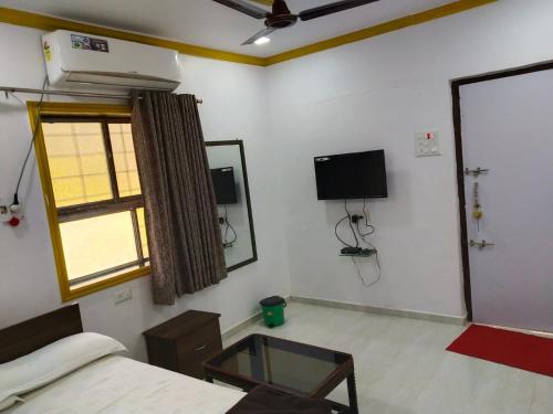 um quarto com uma cama, uma janela e uma televisão em Usha Resort em Pālghar