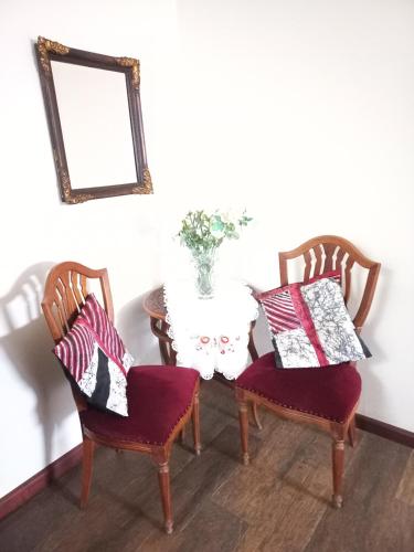 a dining room table with two chairs and a vase of flowers at Hospedagem Aconchegante in Espirito Santo Do Pinhal