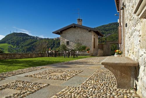 a stone walkway with a building and horses in the background at Ca' Baetti l'Antica Corte in Roncola