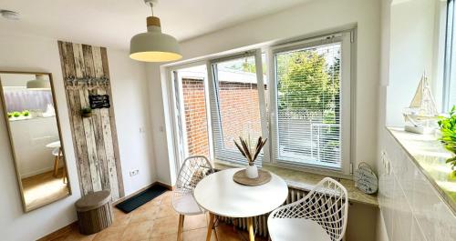 een tafel en stoelen in een kamer met ramen bij Lust auf Meer - Ferienappartement in Cuxhaven