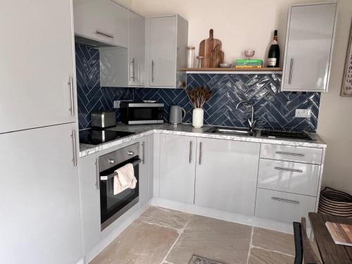 a kitchen with white cabinets and a stove top oven at The Old Nurseries Luxury Guest Suite in Lincoln