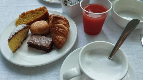 un piatto di cibo con pasticcini e una tazza di caffè di Hotel Pigalle a Riccione