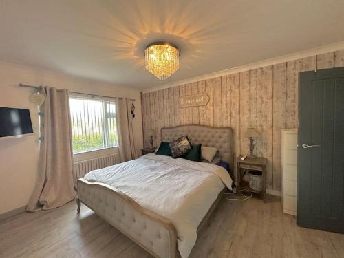 Un dormitorio con una cama grande y una lámpara de araña. en Detached Bungalow Private Hot Tub With Log Burner, en Torquay
