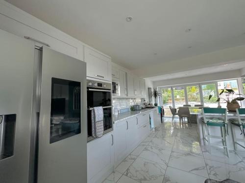 a kitchen with white cabinets and a dining room at Detached Bungalow Private Hot Tub With Log Burner in Torquay