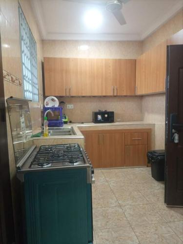 una cocina con estufa verde y armarios de madera en 2 bedroom apartment, en Tema