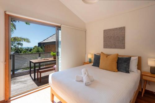 a bedroom with a large white bed with a balcony at The Surf Pad - Oceanstays in Yamba