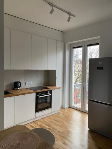 a kitchen with white cabinets and a stainless steel refrigerator at Apartament Otwarta Wrocław in Wrocław