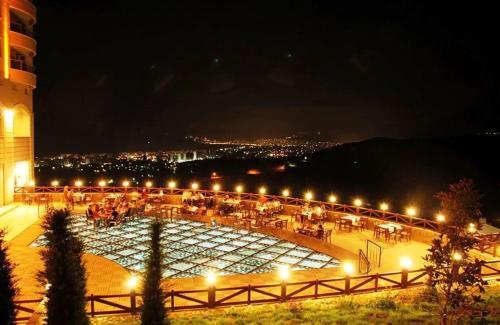 a courtyard with tables and lights at night at Goldcity Otel Kargıcak in Alanya