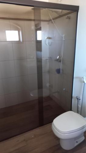 a bathroom with a toilet and a glass shower at Hospedagem Aconchegante in Espirito Santo Do Pinhal