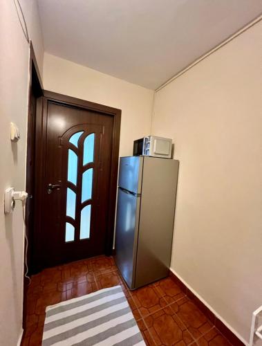 a kitchen with a refrigerator and a door with a microwave at Cozy studio flat in Giurgiu