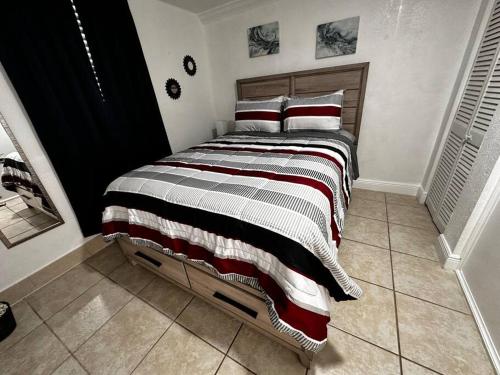 ein Schlafzimmer mit einem großen Bett mit gestreiften Decken und Kissen in der Unterkunft Miami Breeze Studio in Miami Gardens