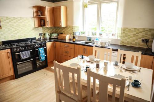 a kitchen with a table with chairs and a stove at Stylishly decorated 3 bed home close to the sea on the Wirral Peninsula in Hoylake