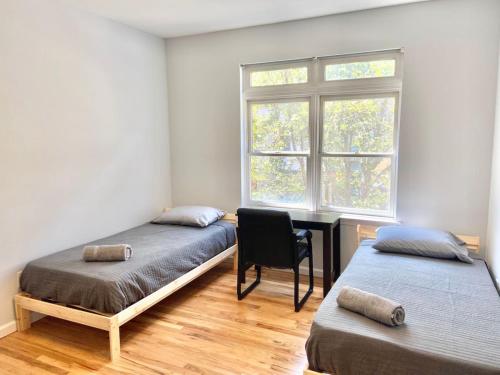 a bedroom with two beds and a desk and a window at 204-Bright 2Bed 2Ba w Stainless Steel Appliances in Hoboken