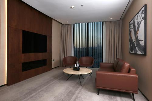 a living room with a couch and a tv and a table at ALMA Hotel Riyadh in Riyadh