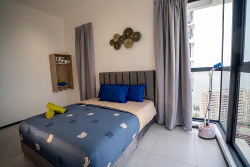 a bedroom with a bed with blue pillows and a window at Seaview Urban suites Georgetown @Penang in Jelutong