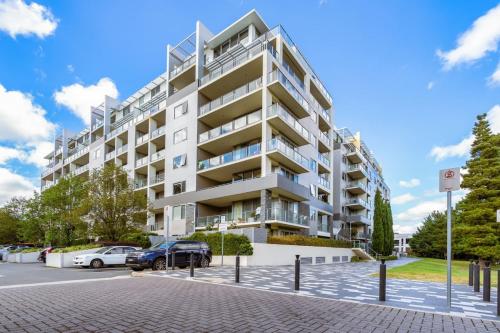 an apartment building with cars parked in a parking lot at Tranquil 2BR APT - Glebe Park View - Hosted by CanStay in Canberra