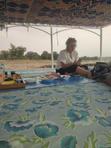 a woman sitting on the floor under an umbrella at Felucca Sailing Boat Overnight Experience in Aswan