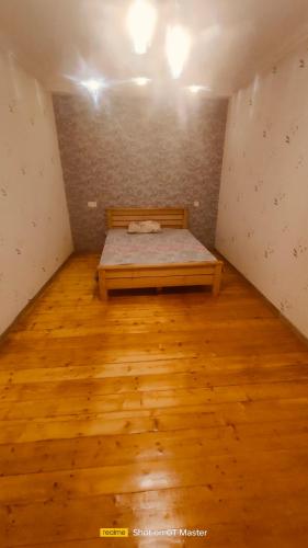 1 dormitorio con 1 cama en una habitación con suelo de madera en Дом для одыха en Tiflis