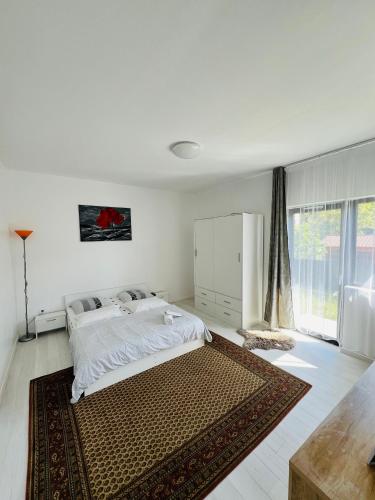 ein weißes Schlafzimmer mit einem Bett und einem großen Fenster in der Unterkunft Apartament zona de case-rezidențiala 2 km de Vivo Mall,curte privata in Baia Mare