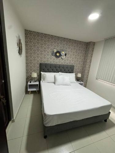 1 Schlafzimmer mit einem großen weißen Bett und 2 Nachttischen in der Unterkunft Lujoso apartamento céntrico in Pereira