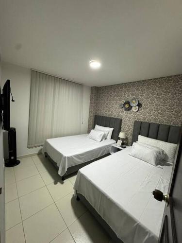 ein Hotelzimmer mit 2 Betten und einem TV in der Unterkunft Lujoso apartamento céntrico in Pereira