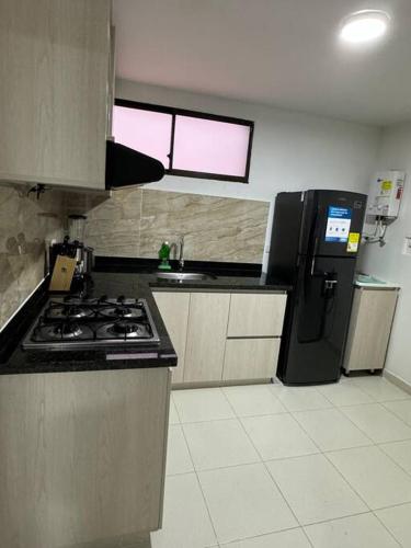 eine Küche mit einem Herd und einem schwarzen Kühlschrank in der Unterkunft Lujoso apartamento céntrico in Pereira