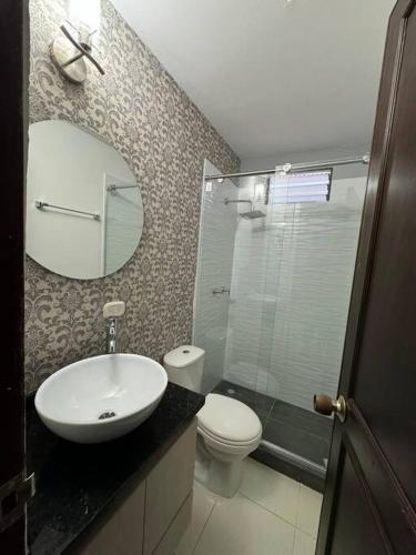 ein Badezimmer mit einem Waschbecken, einem WC und einem Spiegel in der Unterkunft Lujoso apartamento céntrico in Pereira