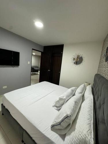 ein Schlafzimmer mit einem großen weißen Bett mit Kissen in der Unterkunft Lujoso apartamento céntrico in Pereira