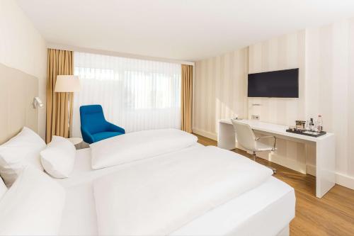 Cette chambre d'hôtel comprend deux lits et une chaise bleue. dans l'établissement NH Erlangen, à Erlangen