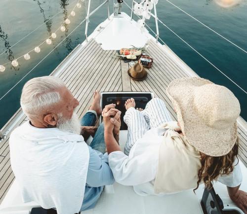 an older couple sitting on a boat looking at a tablet at Hotel Marina Port in Balatonkenese