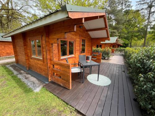 a small wooden cabin with a table and a table at Herberg de Bos in Swalmen