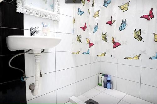 baño con lavabo y mariposas en la pared en Prishtina Guests' en Pristina