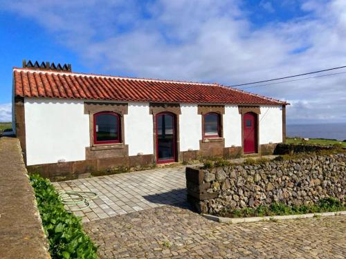 a house with red doors and a stone wall at Casa do Facho in Praia da Vitória
