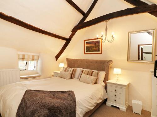 um quarto com uma grande cama branca e um espelho em Larksworthy Cottage em North Tawton