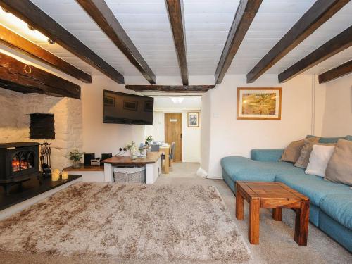 uma sala de estar com um sofá azul e uma lareira em Larksworthy Cottage em North Tawton
