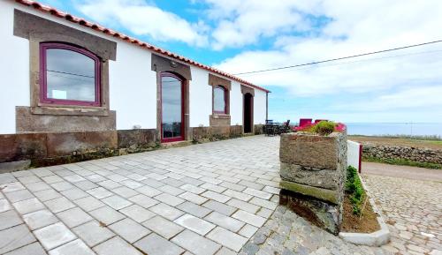 a white building with windows and a brick sidewalk at Casa do Facho in Praia da Vitória