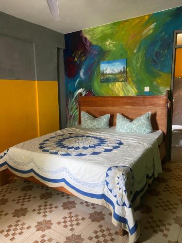 Schlafzimmer mit einem Bett mit Wandgemälde in der Unterkunft Bruks Guest House in Kumasi