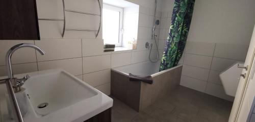 uma casa de banho com um lavatório, uma banheira e uma janela em NICEprice 24h em Oberhofen im Inntal